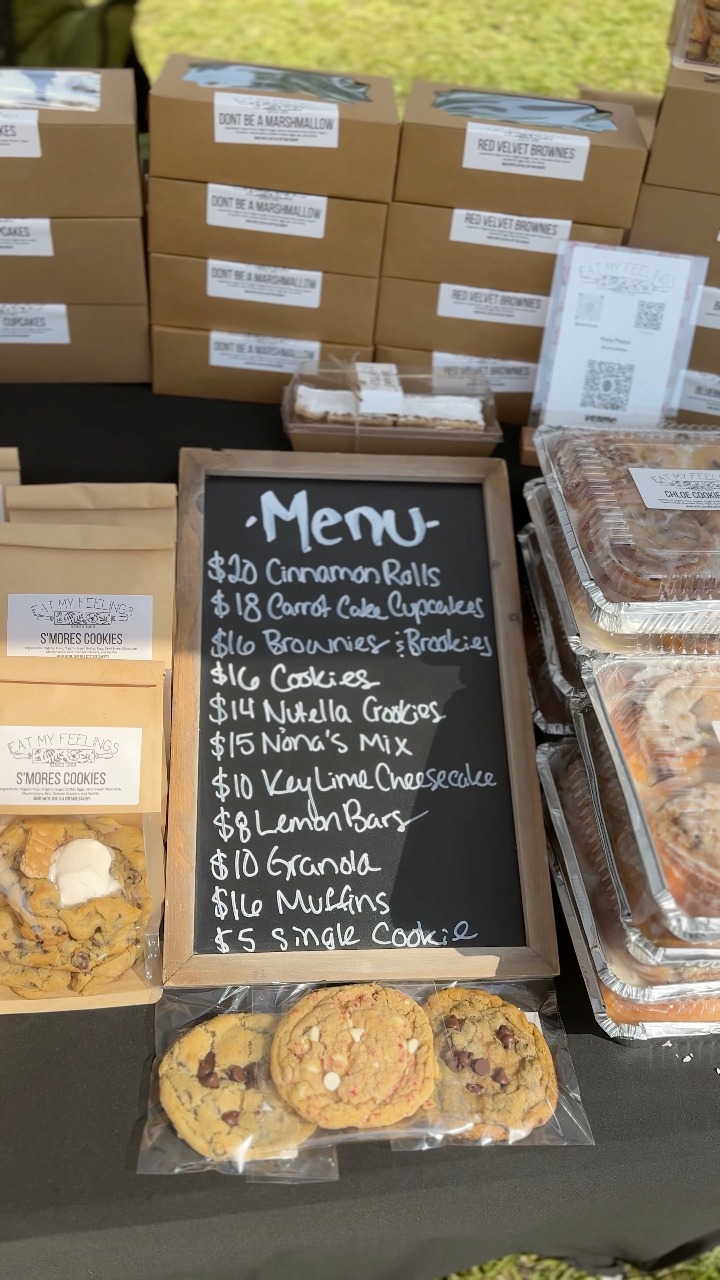 Eat My Feelings market display with a handwritten menu and packaged baked goods